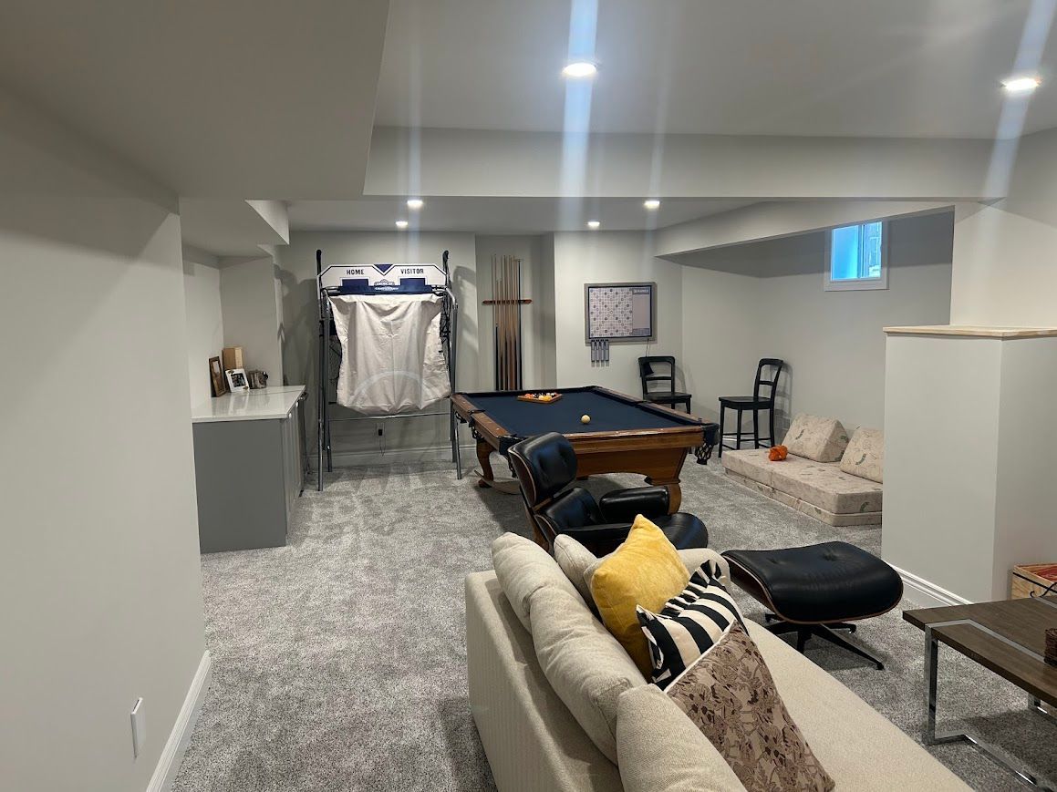 Basement with a pool table, sofa, gray carpet, and a small window.