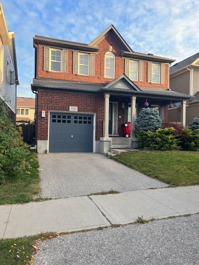 Two-story brick house with a gray garage door and a concrete driveway.