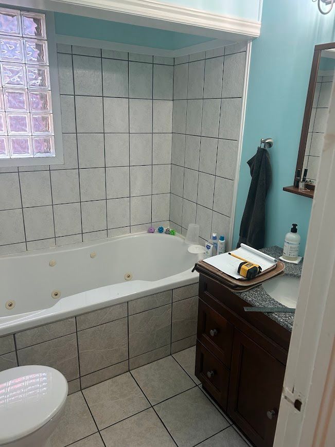 Bathroom with white tile, a bathtub, dark wood vanity, and a blue wall.