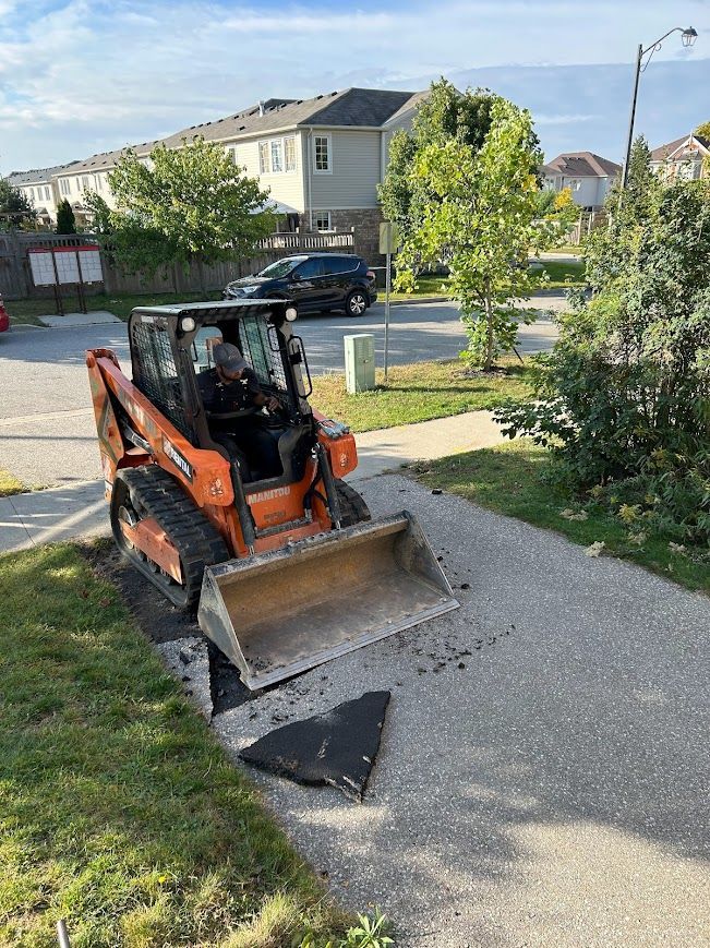 Orange skid steer removing pavement on a sidewalk, residential area.