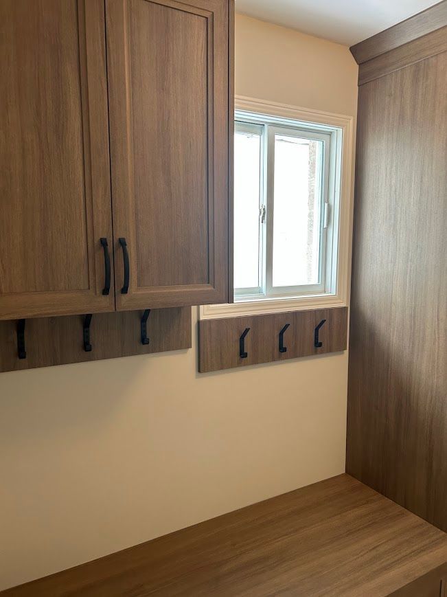 Wooden cabinetry with hooks, a bench, and a small window.