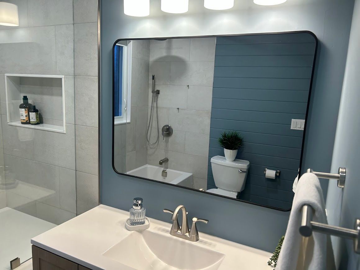 Bathroom with blue walls, a large mirror, a white sink, and a toilet.