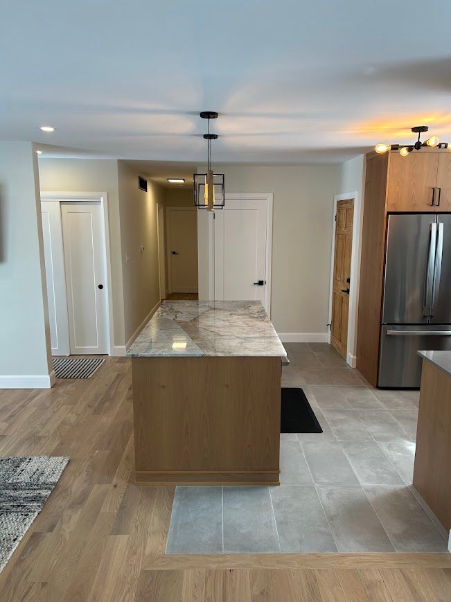 Kitchen with wooden island, stainless steel fridge, light wood floors, and neutral walls.