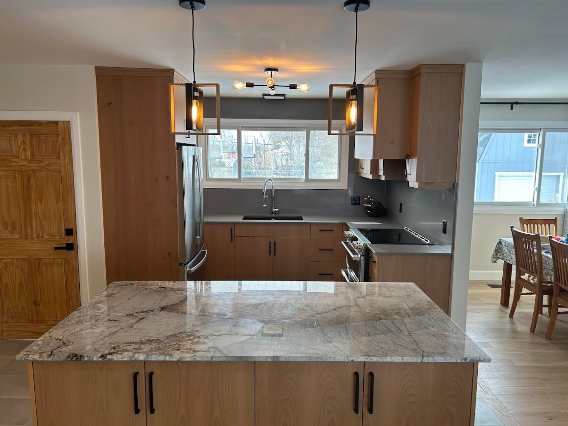 Kitchen with light wood cabinets, granite countertops, and two pendant lights over the island.
