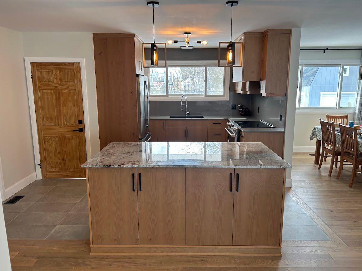 Kitchen with wood cabinets, island, granite countertop, stainless steel appliances, and wood floor.