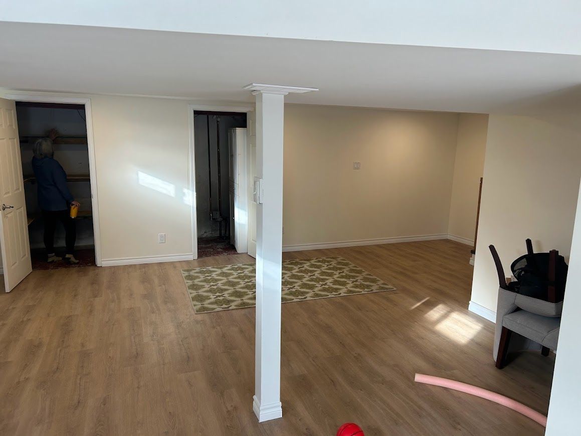 Interior room with light-colored walls and flooring, a white support beam, and a person in a doorway.