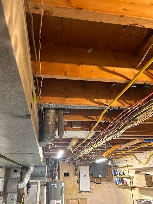 Basement ceiling showing exposed joists, ductwork, wiring, and a water heater.