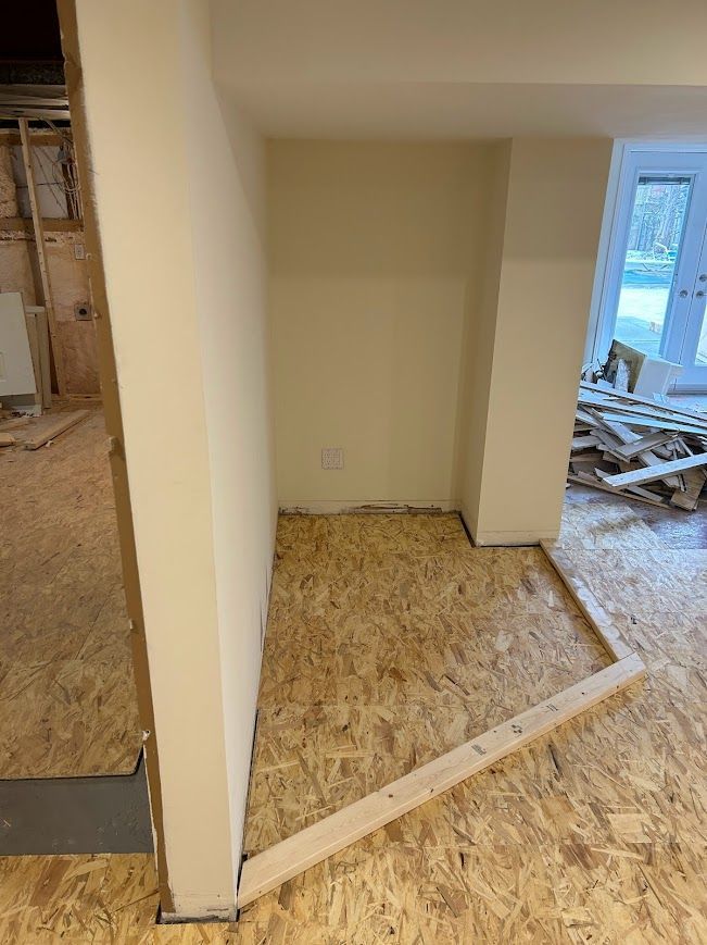 Interior construction: unfinished room with wooden flooring and exposed walls, doorway to the right.