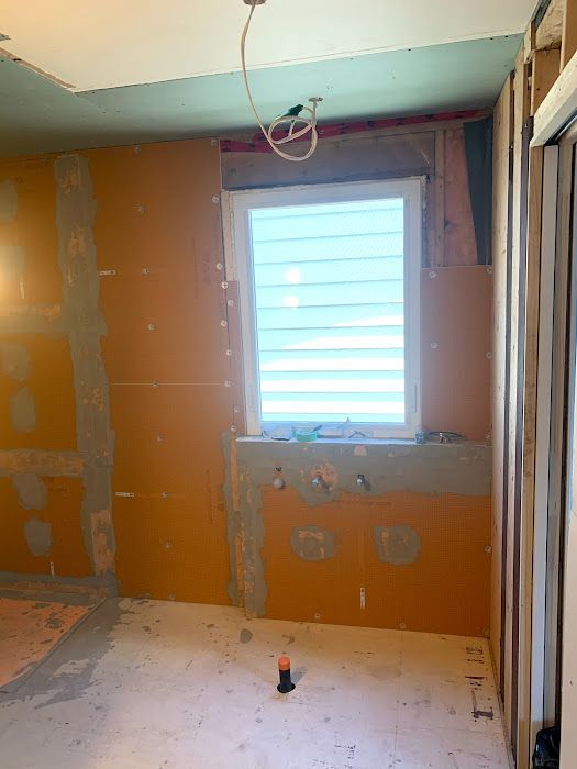Bathroom under construction; orange wall panels around a window, exposed studs. Electrical wiring visible.