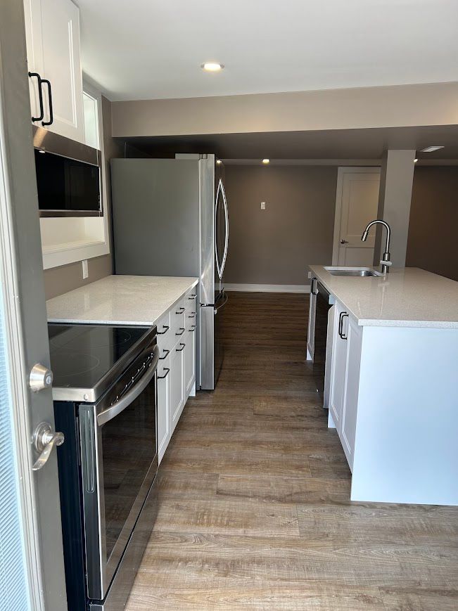 Modern kitchen with white cabinets, stainless steel appliances, and island.