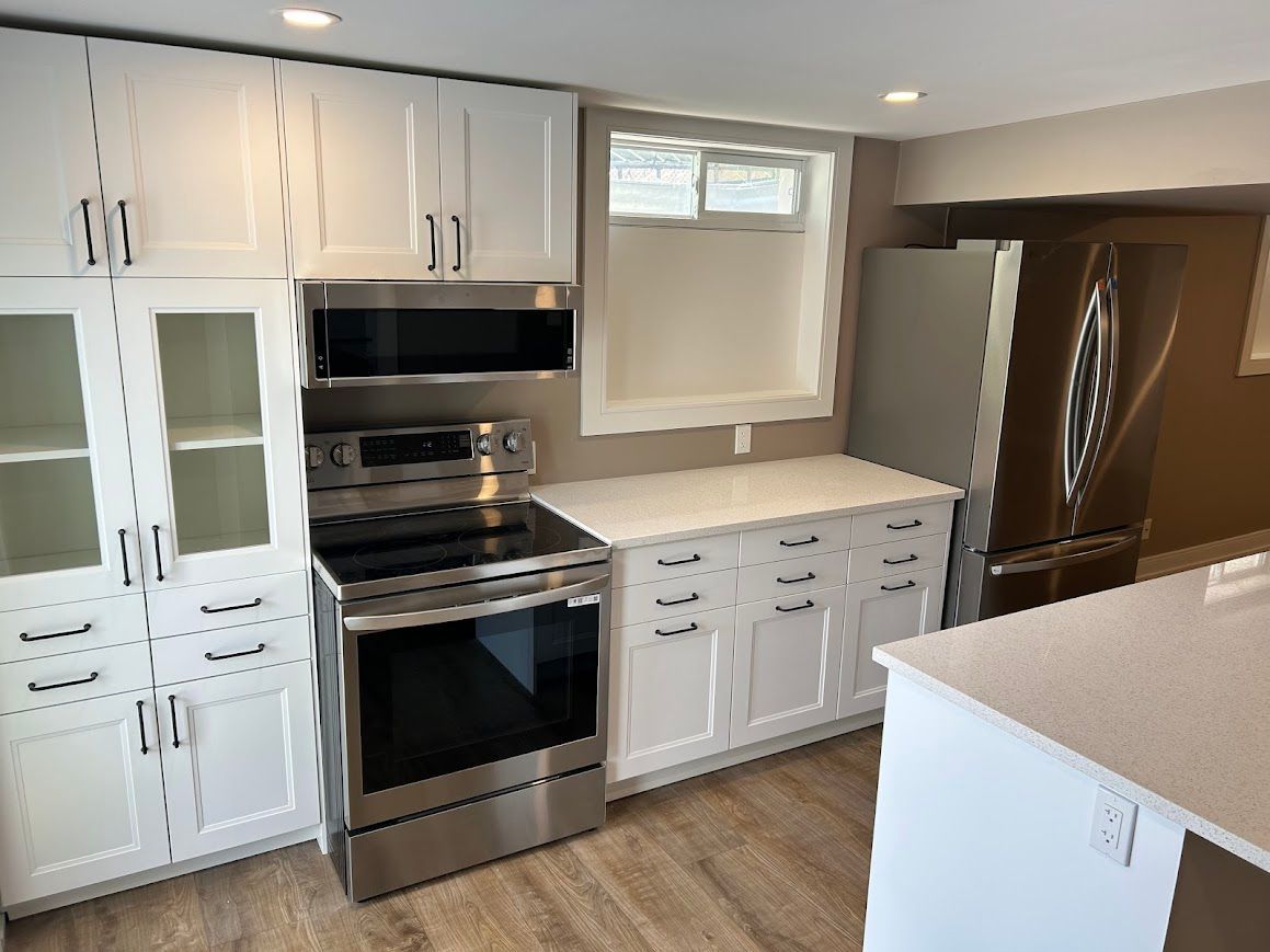 White kitchen with stainless steel appliances, white cabinets, and a window.