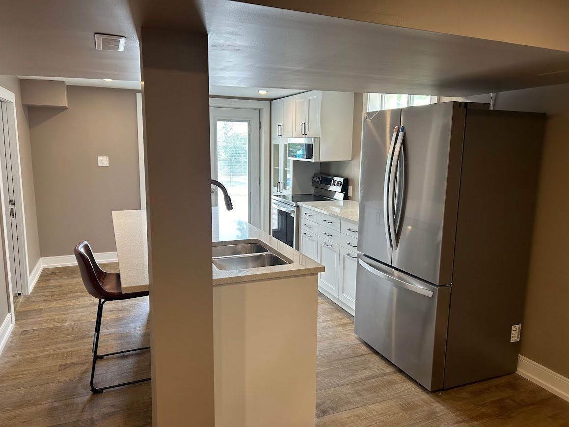 Small kitchen with stainless steel appliances, light cabinets, and a sink island.