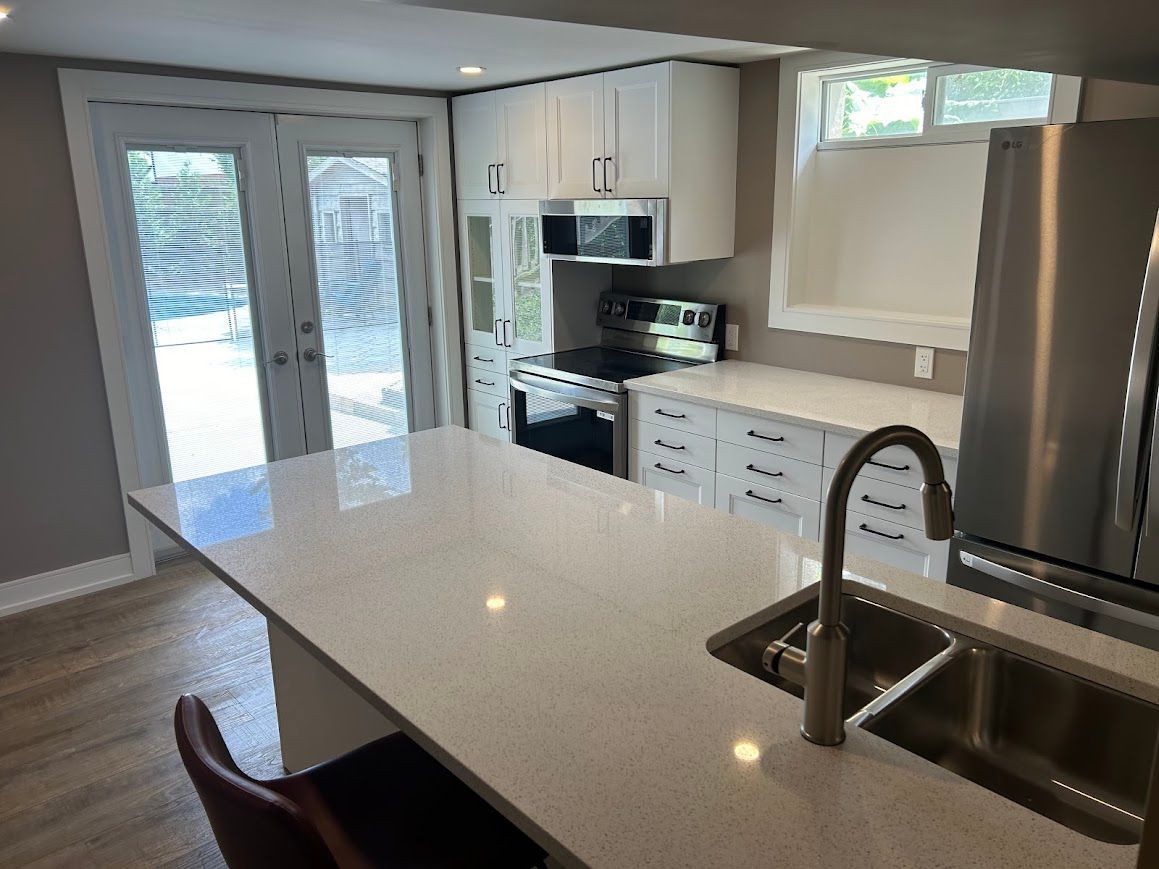Modern kitchen with white cabinets, stainless steel appliances, and a quartz countertop island.