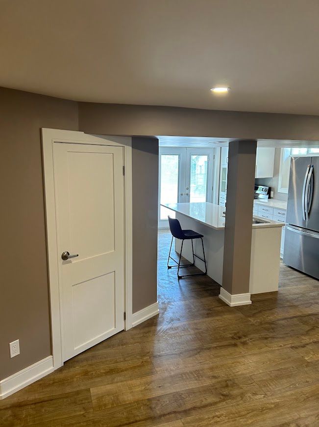 Interior view: doorway to a kitchen with a breakfast bar, white cabinets, and stainless steel appliances.