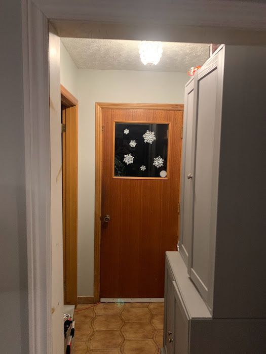 Hallway with brown door, cabinet, and doorway on the left.