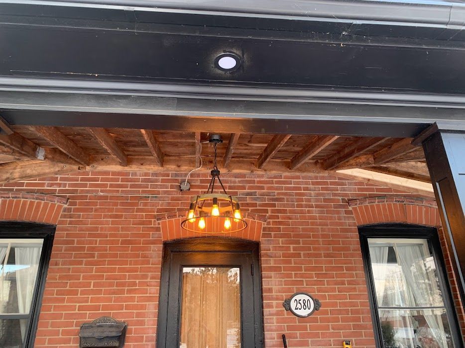 Brick building entrance with a hanging light fixture and wooden ceiling.