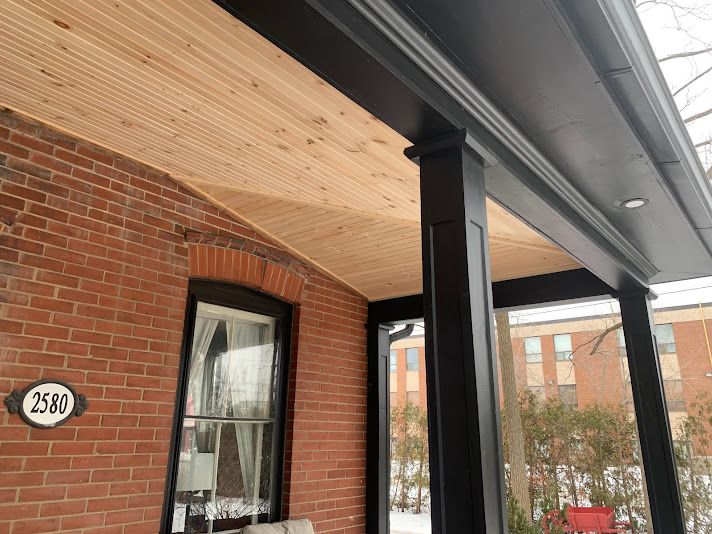 Brick porch with black columns, wood ceiling, and address 2580.
