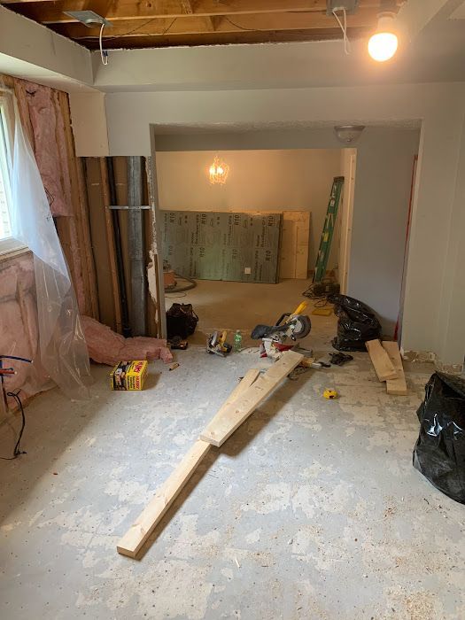 Basement room under construction: exposed framing, debris, and toys scattered on the floor.
