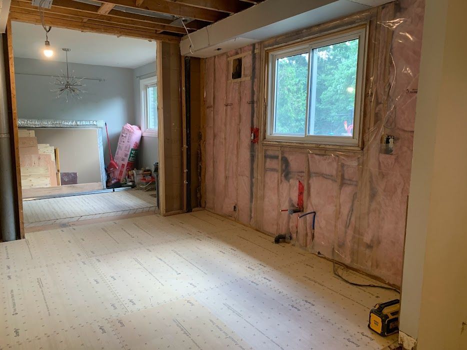 Room under construction; exposed insulation, window, and new wood flooring.