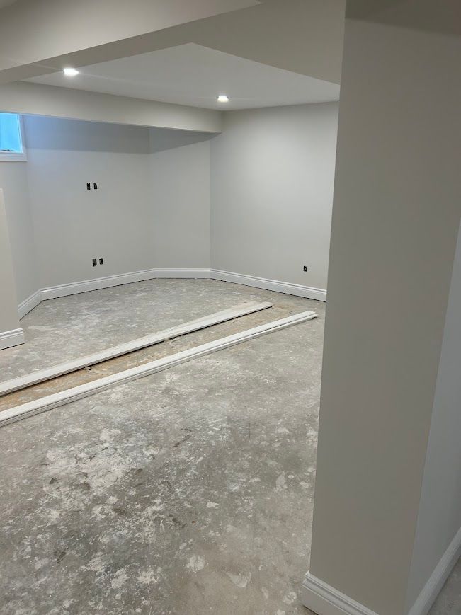 Empty unfinished basement room with concrete floor, white walls, and trim.