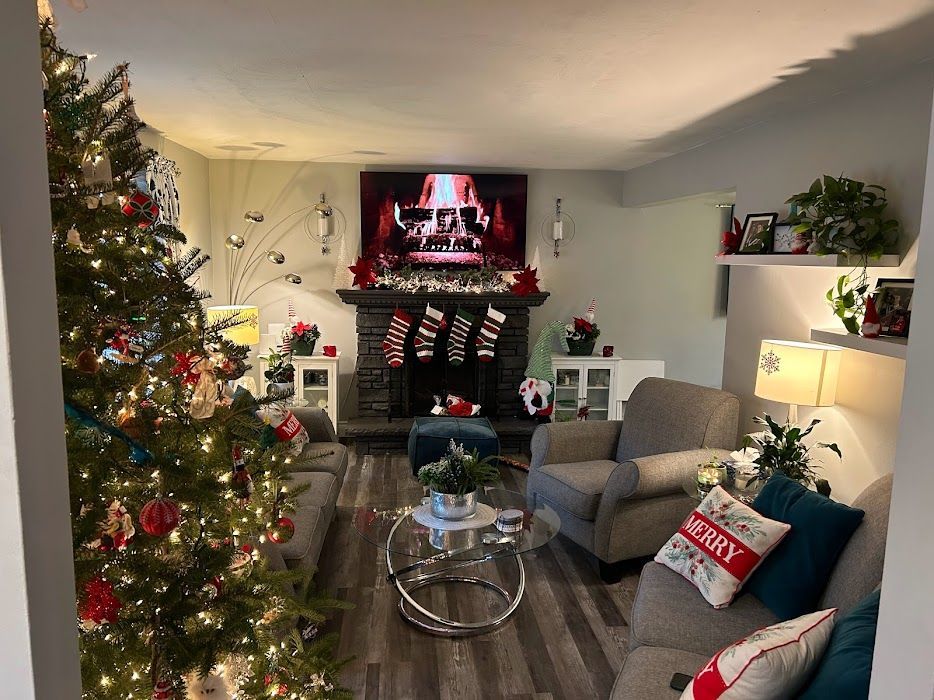 Festive living room with Christmas tree, decorated fireplace, sofas, and festive decor.