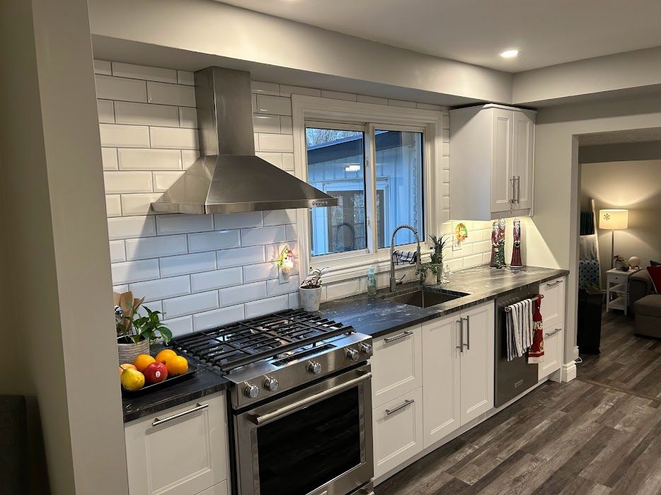 Modern kitchen with white cabinets, stainless steel appliances, and dark countertops.
