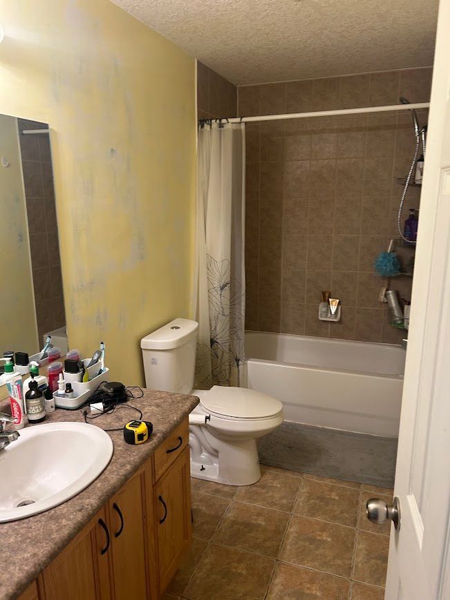 Bathroom with a toilet, sink, bathtub, and shower. Yellow wall, brown tile.