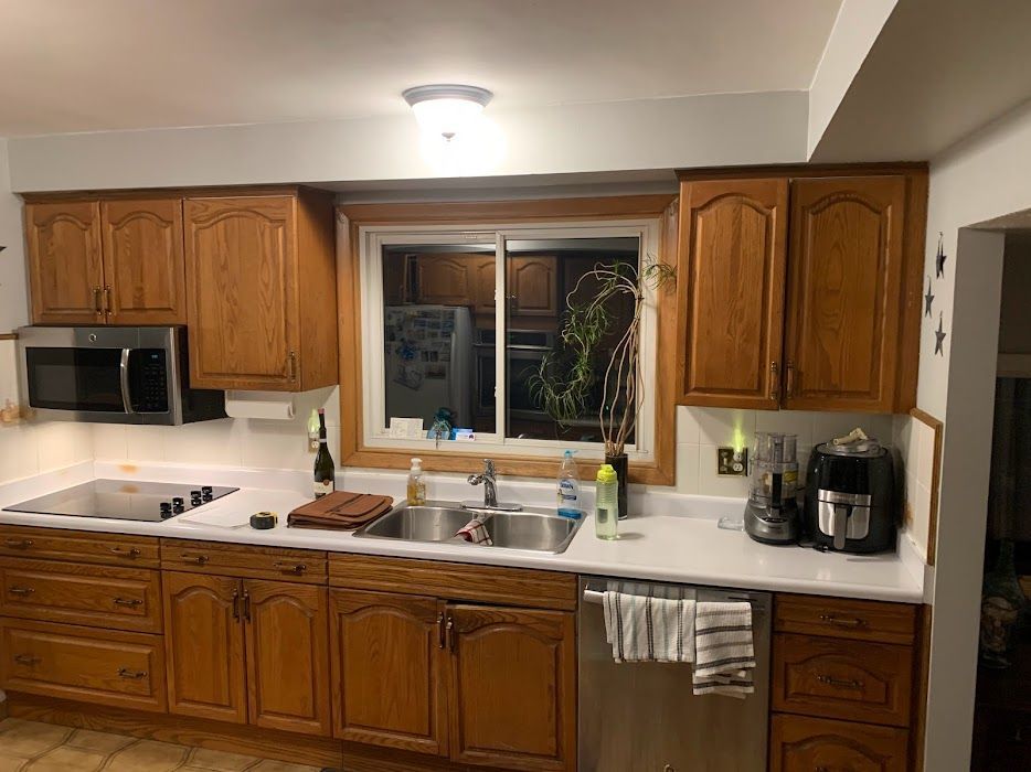 Kitchen with oak cabinets, white countertops, stainless steel appliances, and a window over the sink.