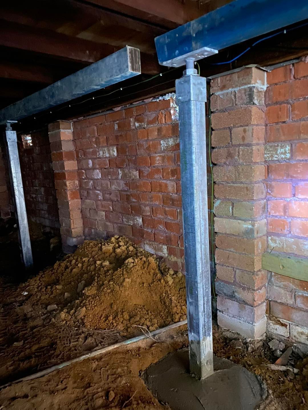 A brick wall with a metal post in the middle of it.