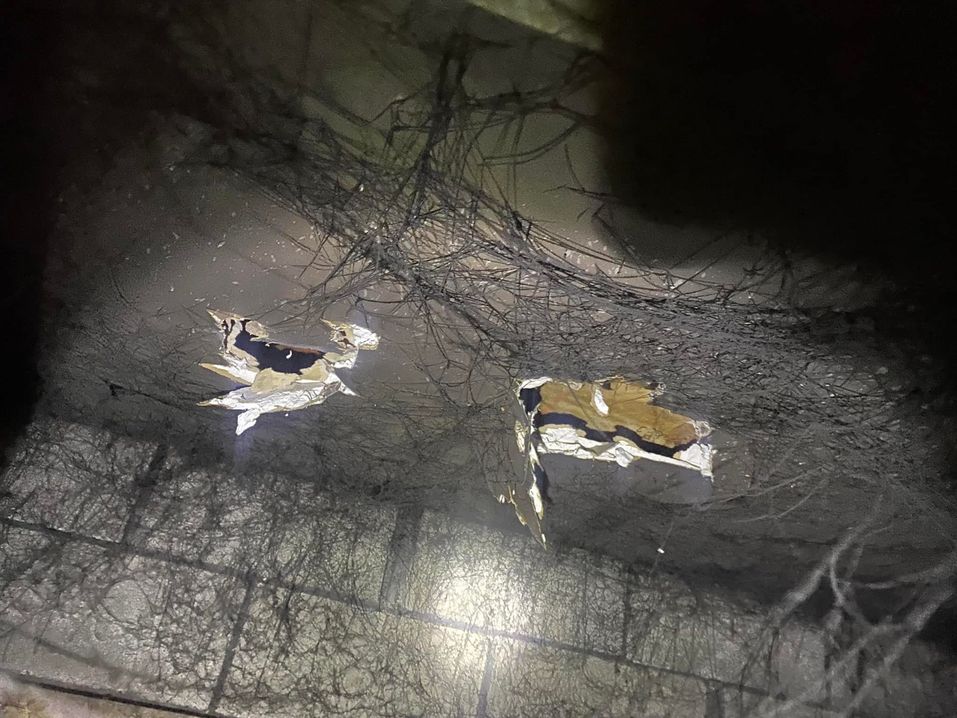 Two holes in a dark ceiling covered in cobwebs, potentially in an abandoned building.