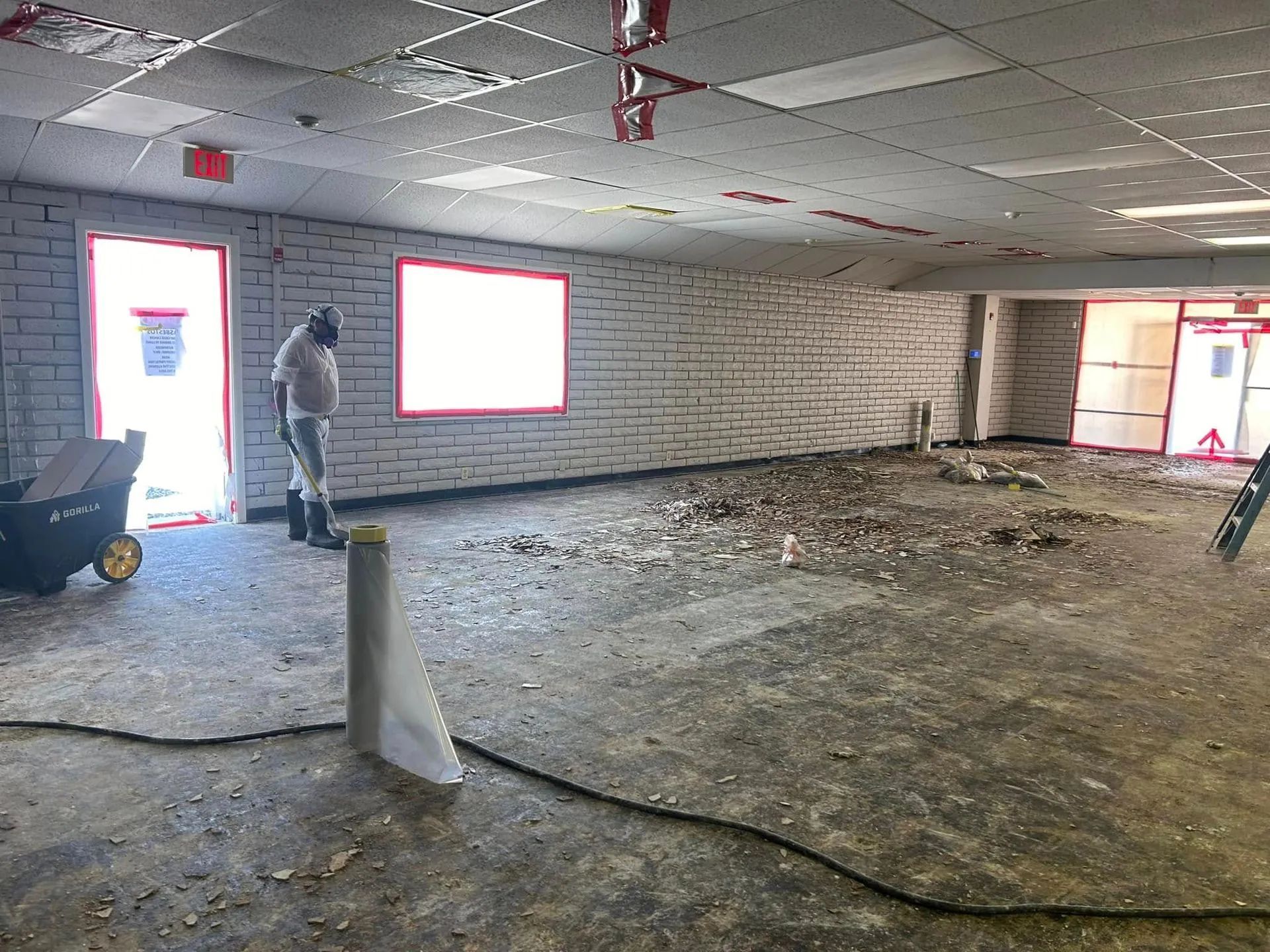 Construction site: Interior view of a room with exposed walls, debris on the floor, and a worker.