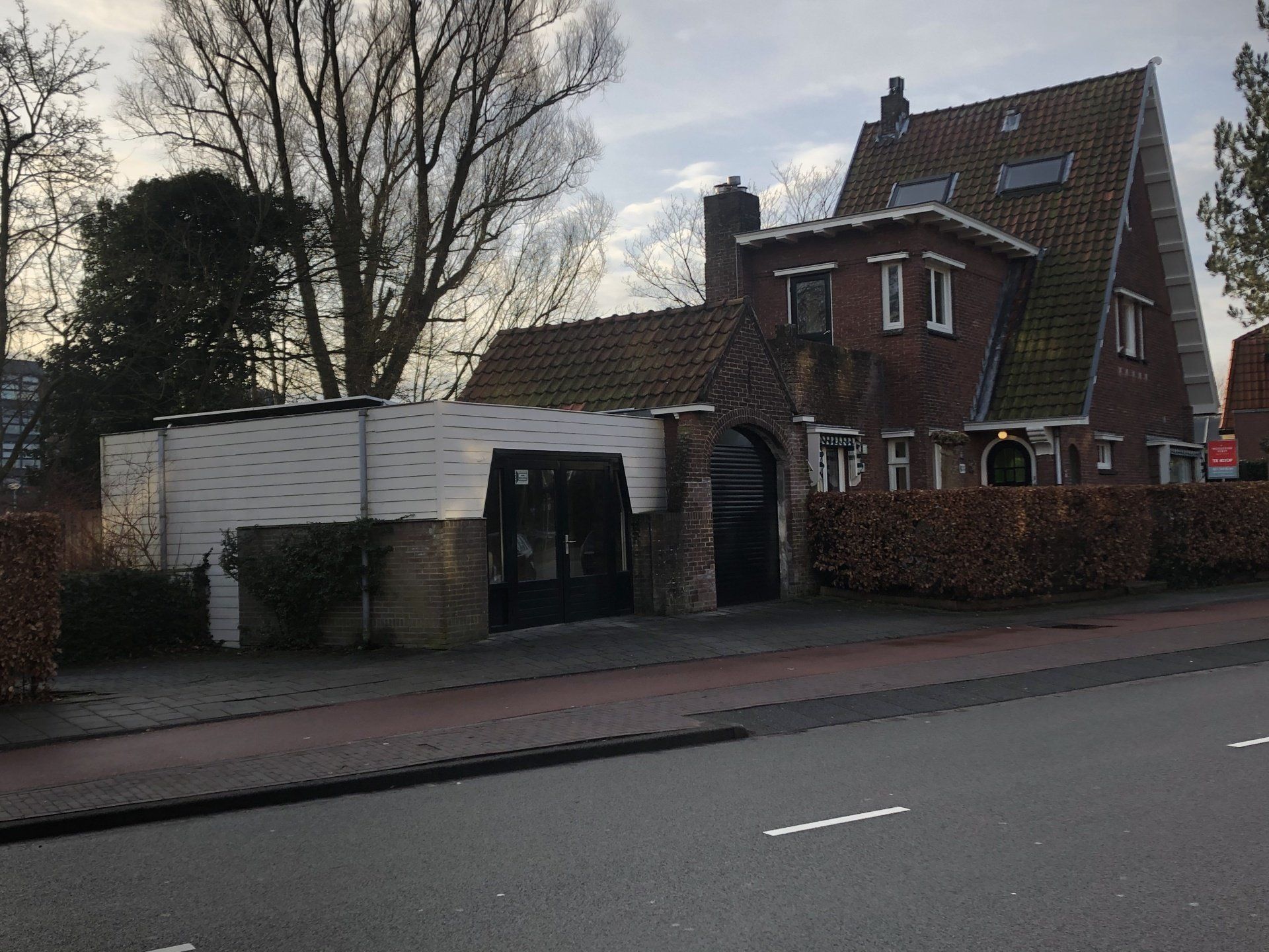 Aan de kant van een weg staat een bakstenen huis met een groendak