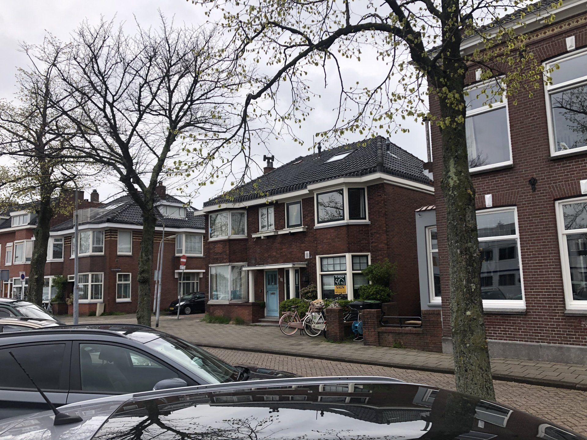 Voor een rij bakstenen huizen staat een auto geparkeerd.