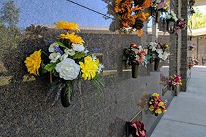 A bunch of flowers are hanging on a wall in a cemetery.