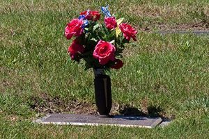 A vase of flowers is sitting on a grave in a cemetery.