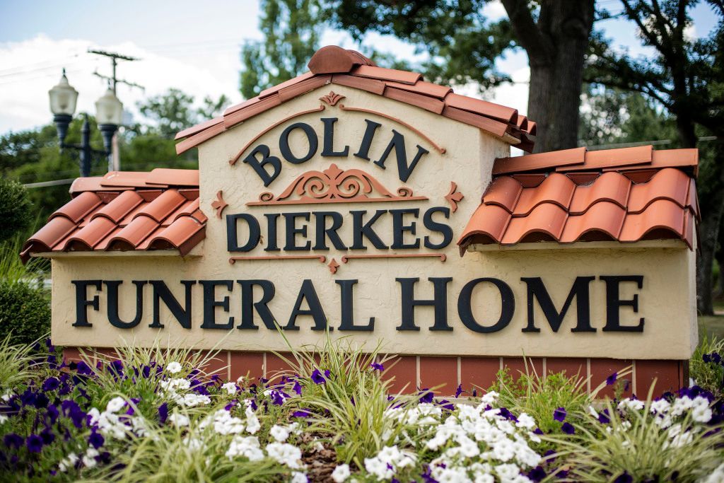 A sign for bolin dierkes funeral home is surrounded by flowers