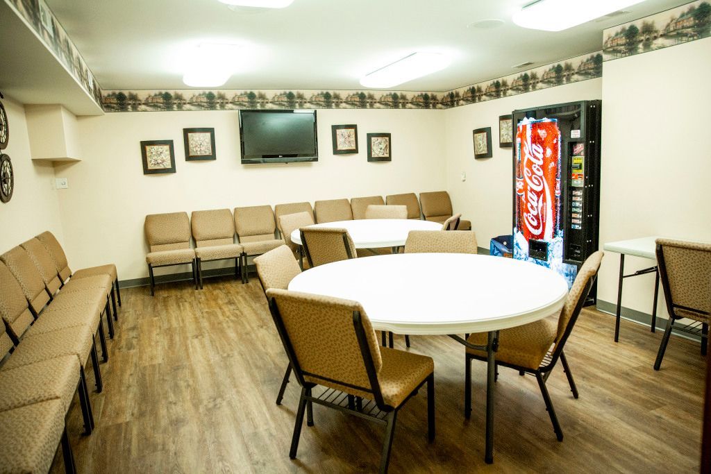 A room with tables and chairs and a coca cola vending machine