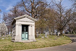 A small white building with a green door in a cemetery.