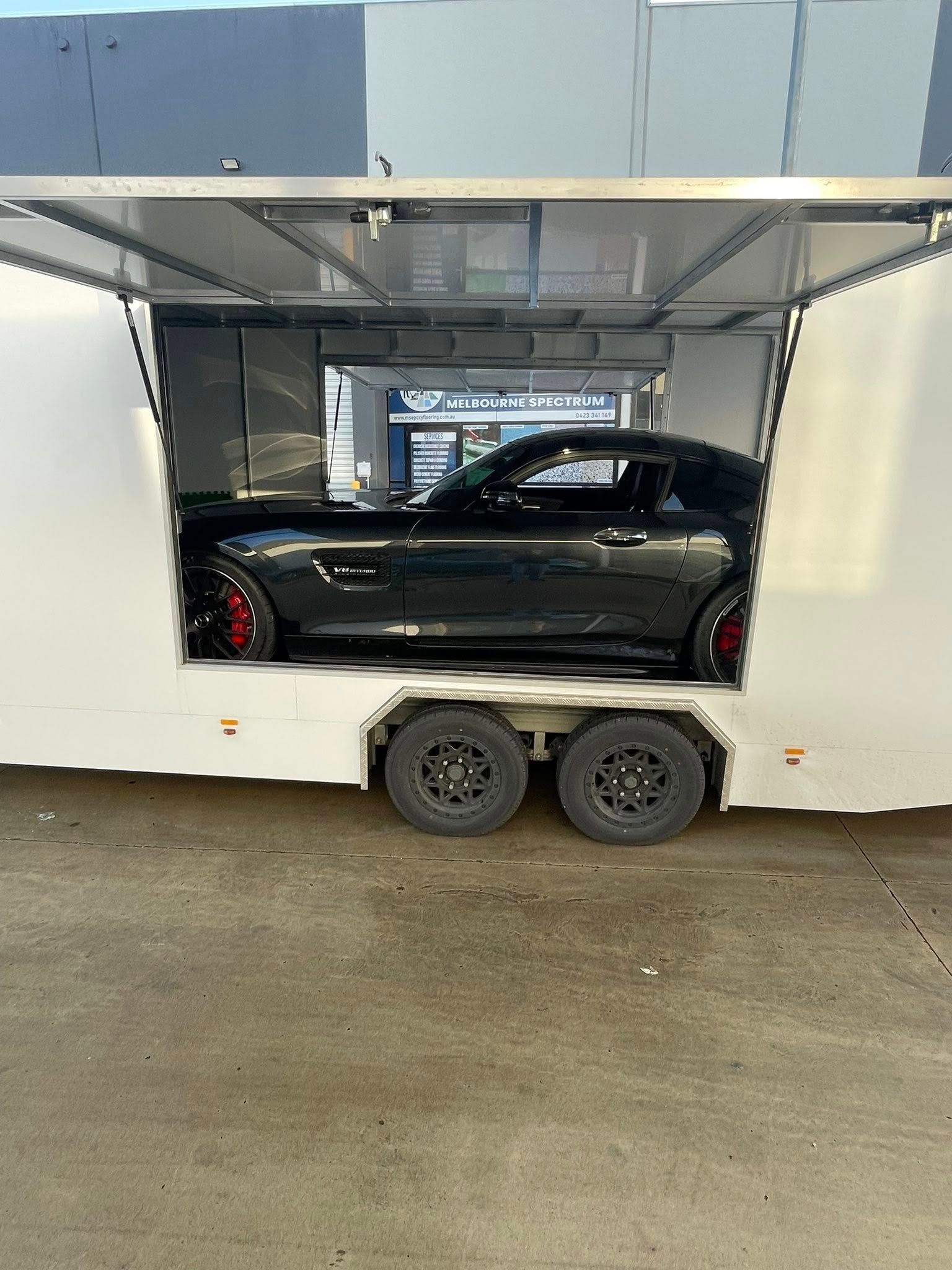 Black Sports Car Inside a White Car Transport Trailer — Full Throttle Enclosed Car Transport in Sydney, NSW