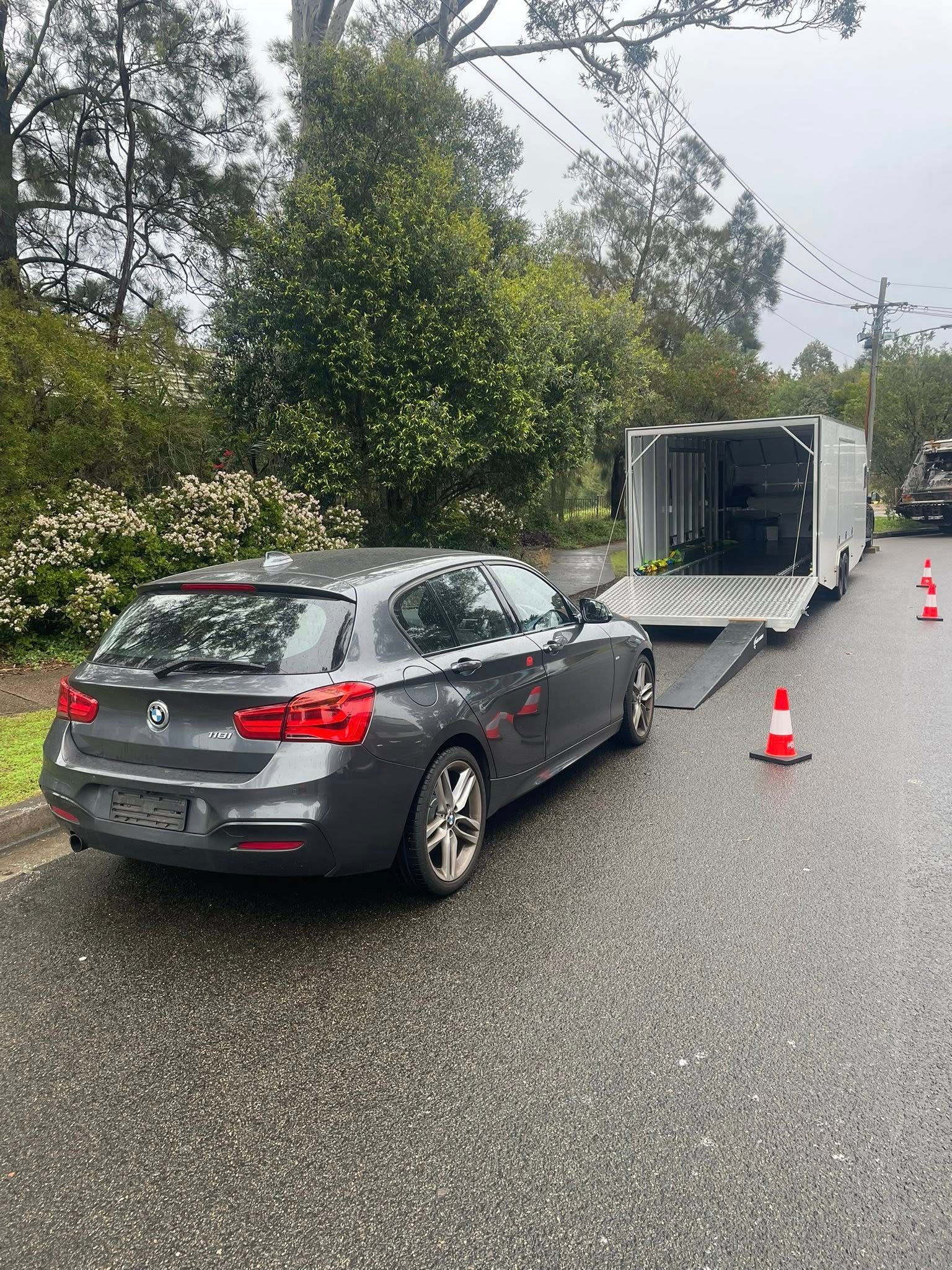 Grey BMW Wagon Attached to A White Trailer on A Wet Street — Full Throttle Enclosed Car Transport in Newcastle, NSW