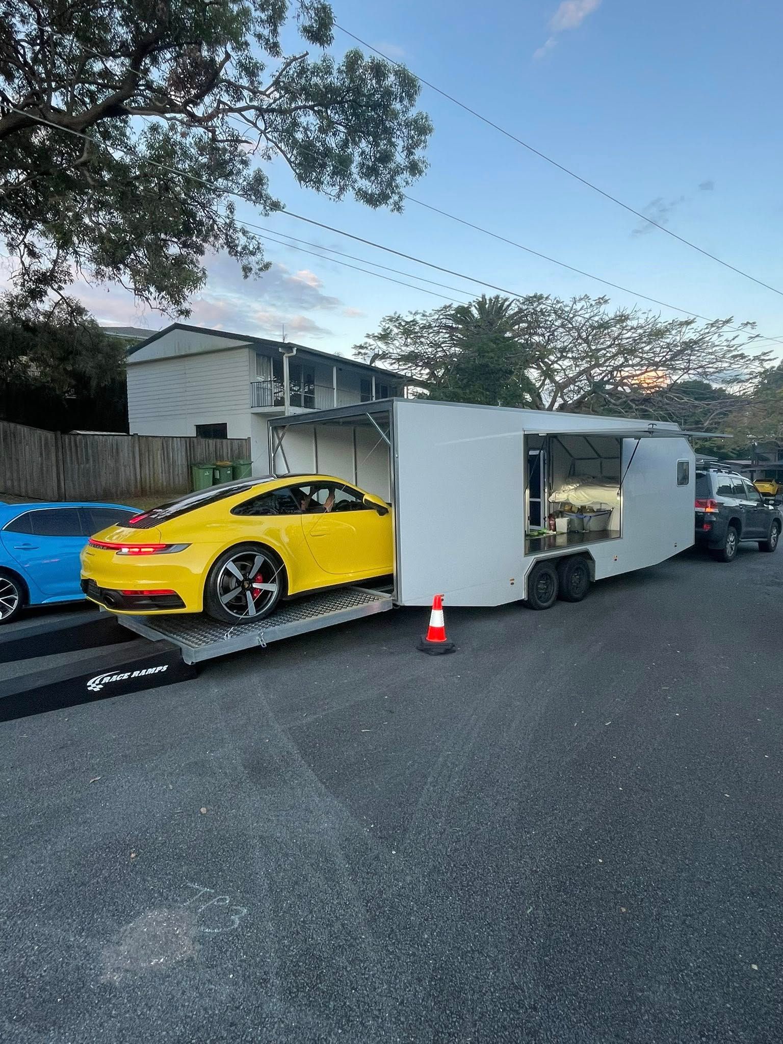 Yellow sports car on a ramp, being loaded into a white trailer — Full Throttle Enclosed Car Transport in Kilmore, VIC