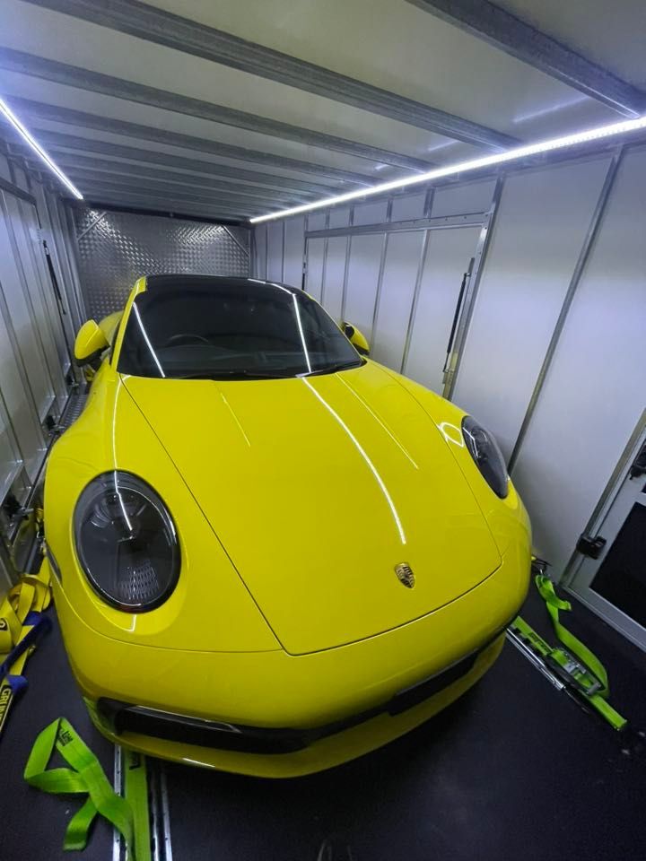 Yellow Porsche sports car inside a trailer, secured with tie-down straps — Full Throttle Enclosed Car Transport in Kilmore, VIC