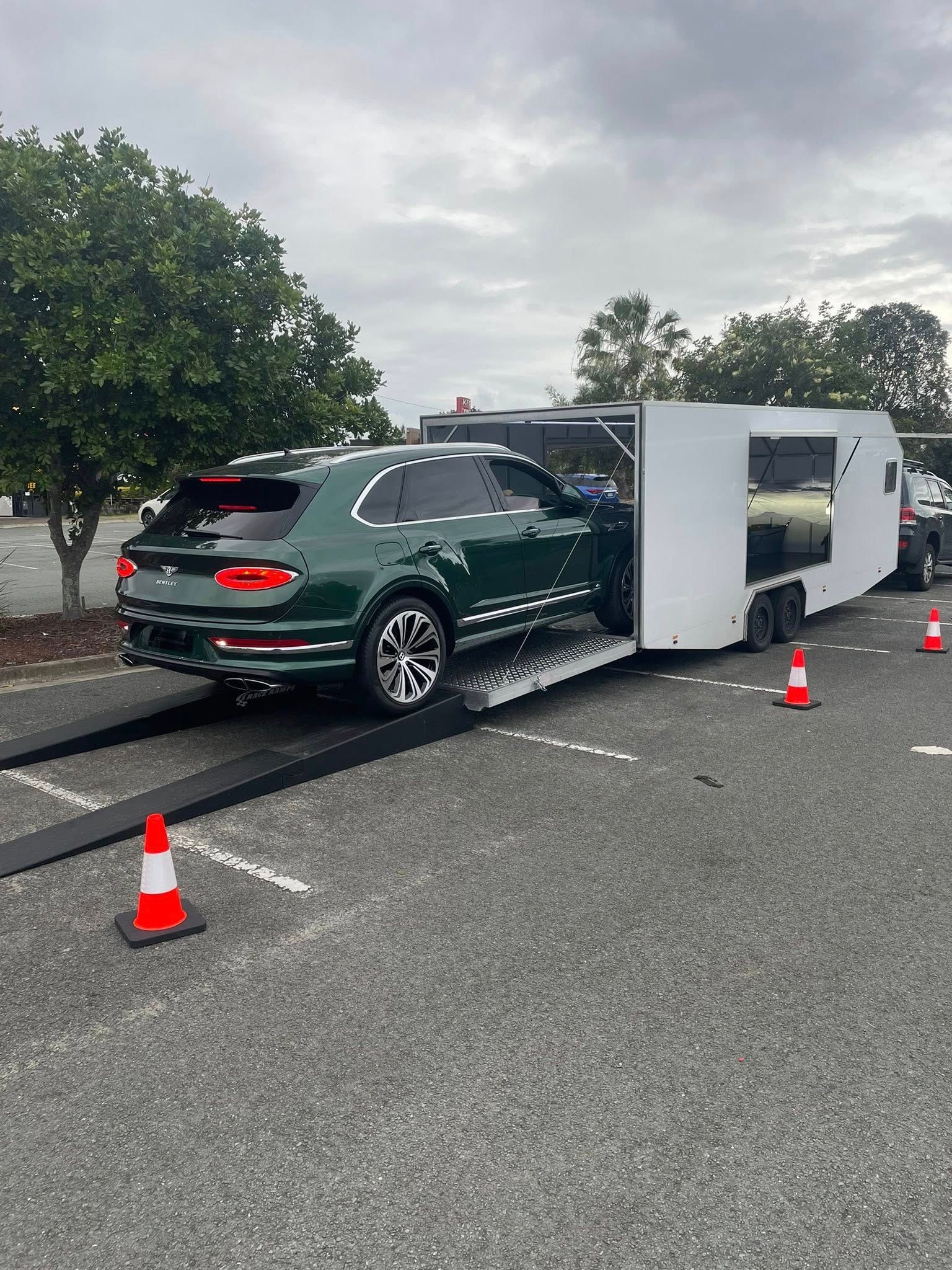 Green Bentley SUV being loaded onto a white enclosed car hauler in a parking lot — Full Throttle Enclosed Car Transport in Kilmore, VIC
