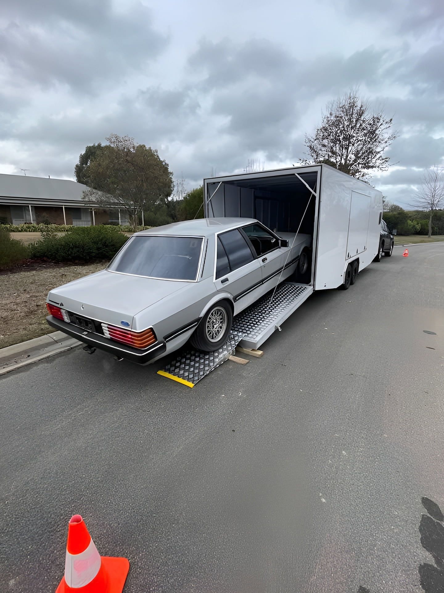 Silver classic car on a ramp, being loaded into a white enclosed trailer on a street — Full Throttle Enclosed Car Transport in Kilmore, VIC