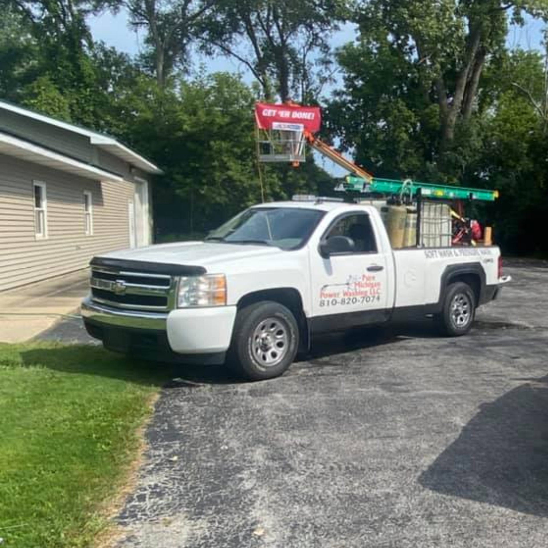 Pressure Pros and Soft Washing - White pickup truck with lift equipment parked near a building.