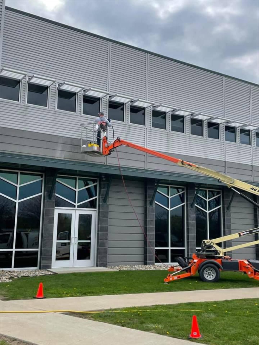 Pressure Pros Soft Washing LLC | man is painting the side of a building with a crane.