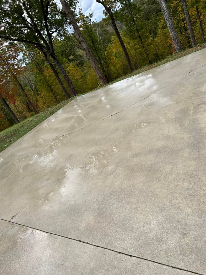 Pressure Pros Soft Washing LLC | concrete driveway with trees in the background.