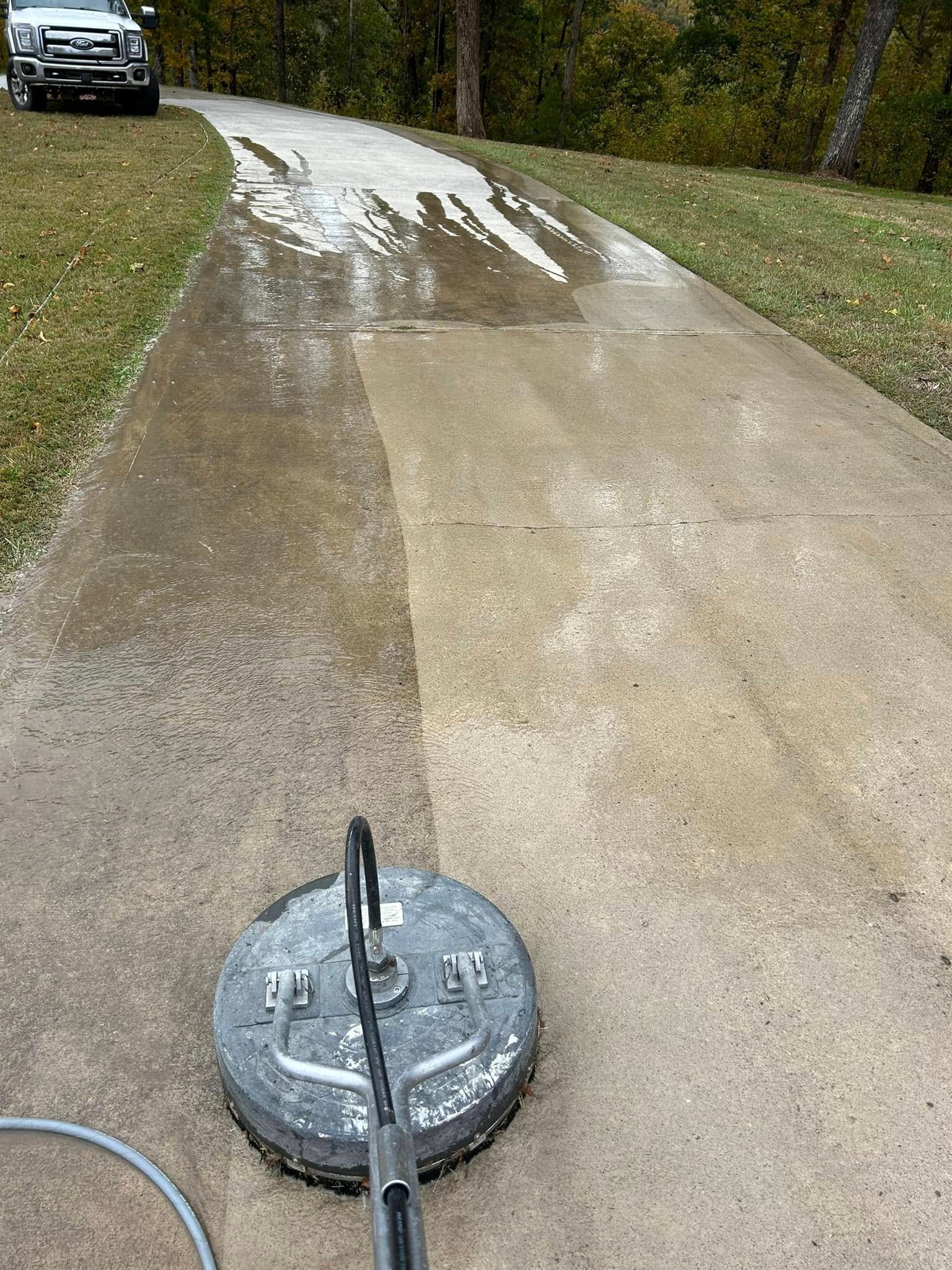 Pressure Pros Soft Washing LLC | concrete driveway is being cleaned with a pressure washer.