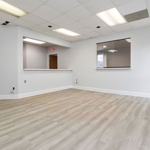 Pressure Pros and Soft Washing -Empty office with gray walls and wood-look floors.