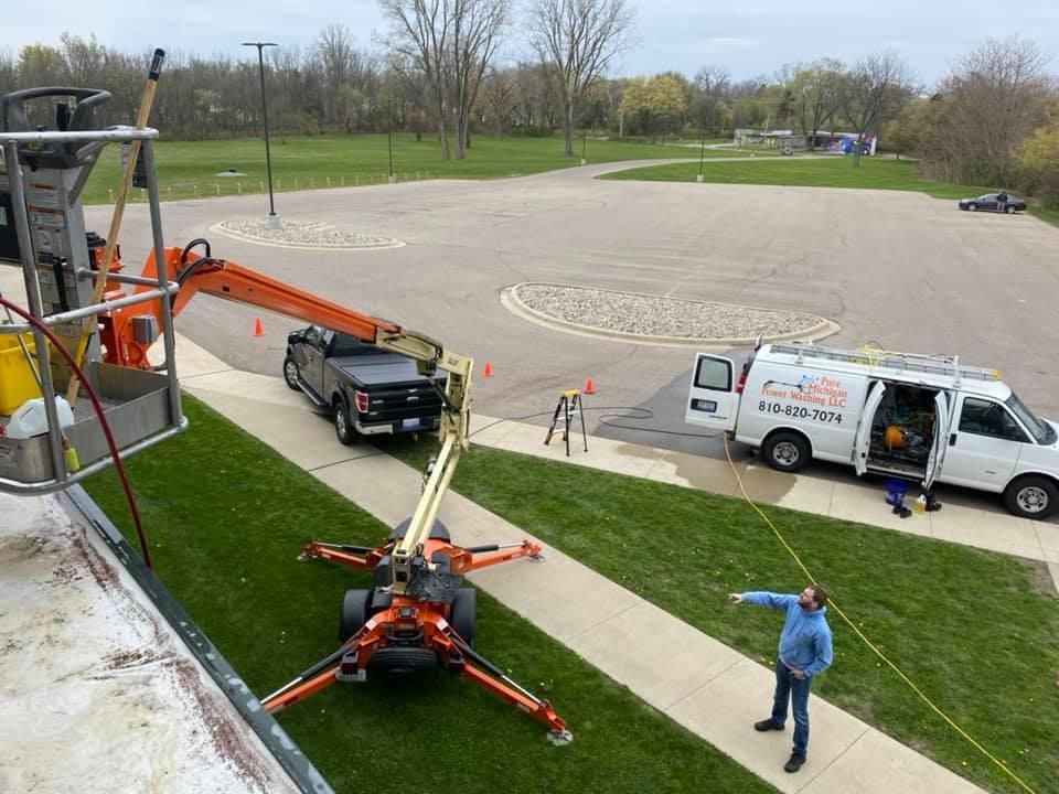 Pressure Pros Soft Washing LLC | man is standing on a sidewalk next to a crane and a van.